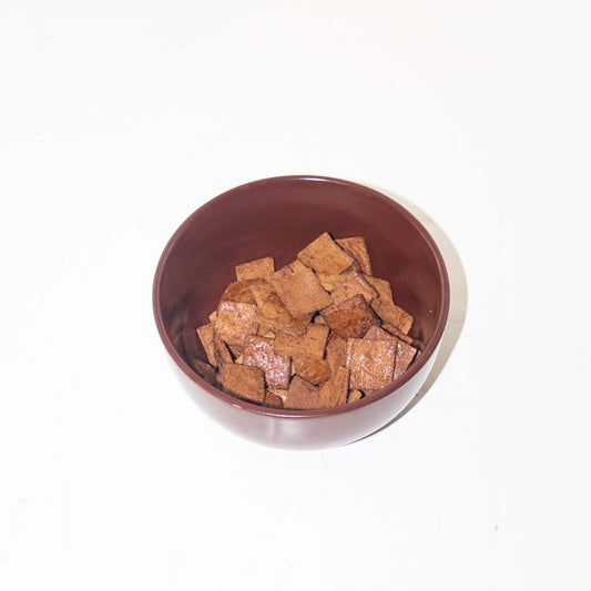 Brown bowl filled with cereal pieces on a white background