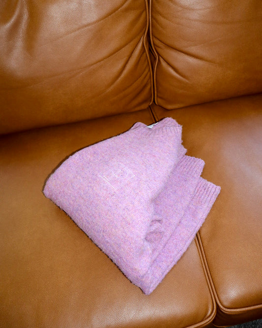 Folded pink sweater on a brown leather couch