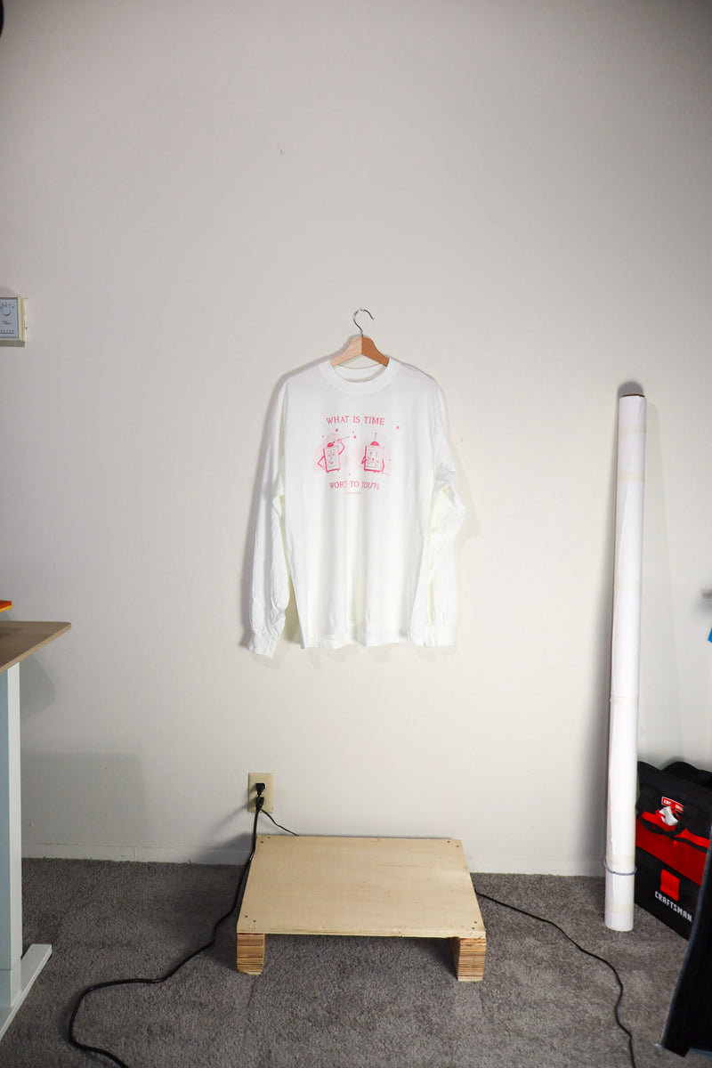 White long-sleeve shirt with red design on a hanger against a white wall.