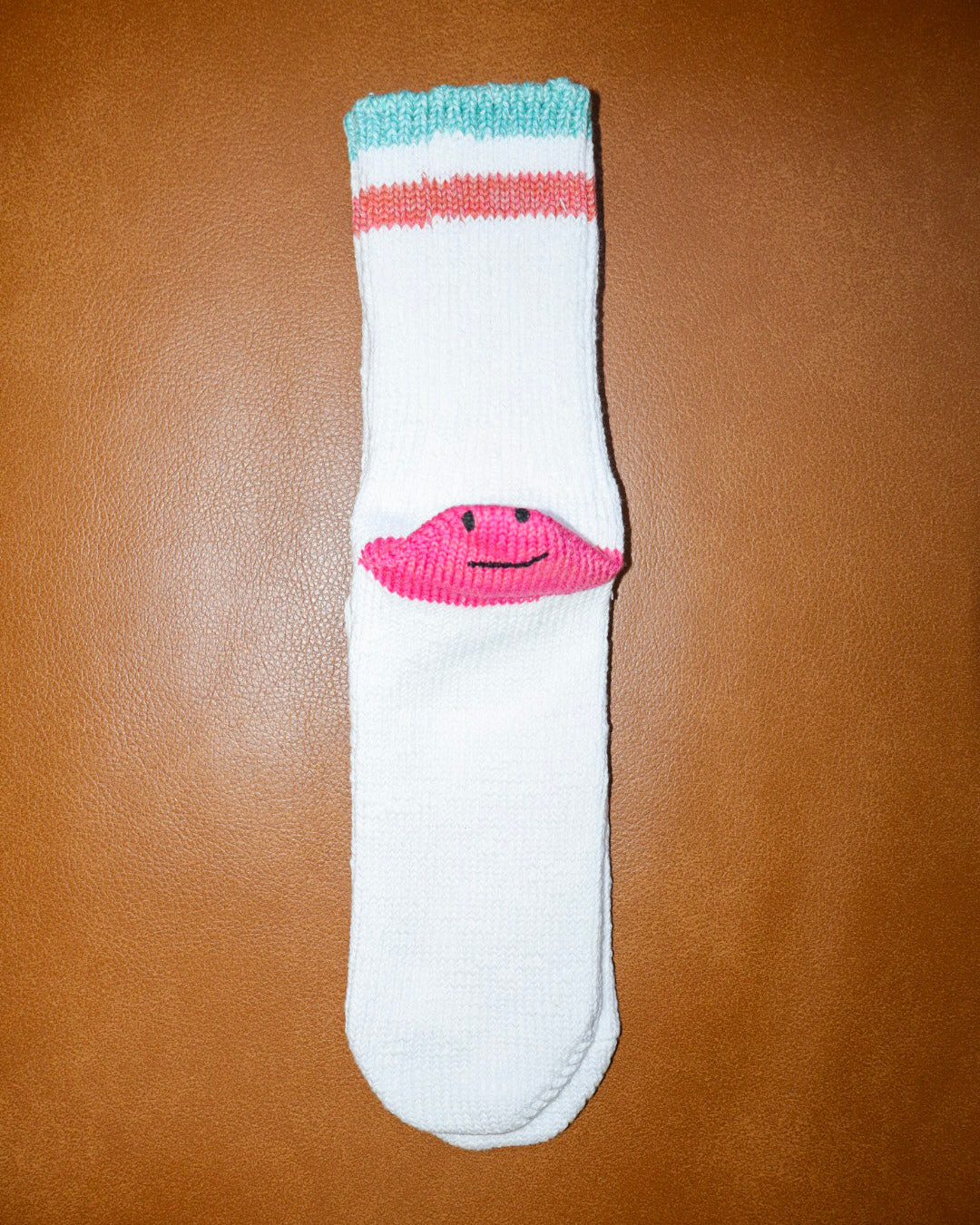 White sock with pink flamingo design on a brown surface