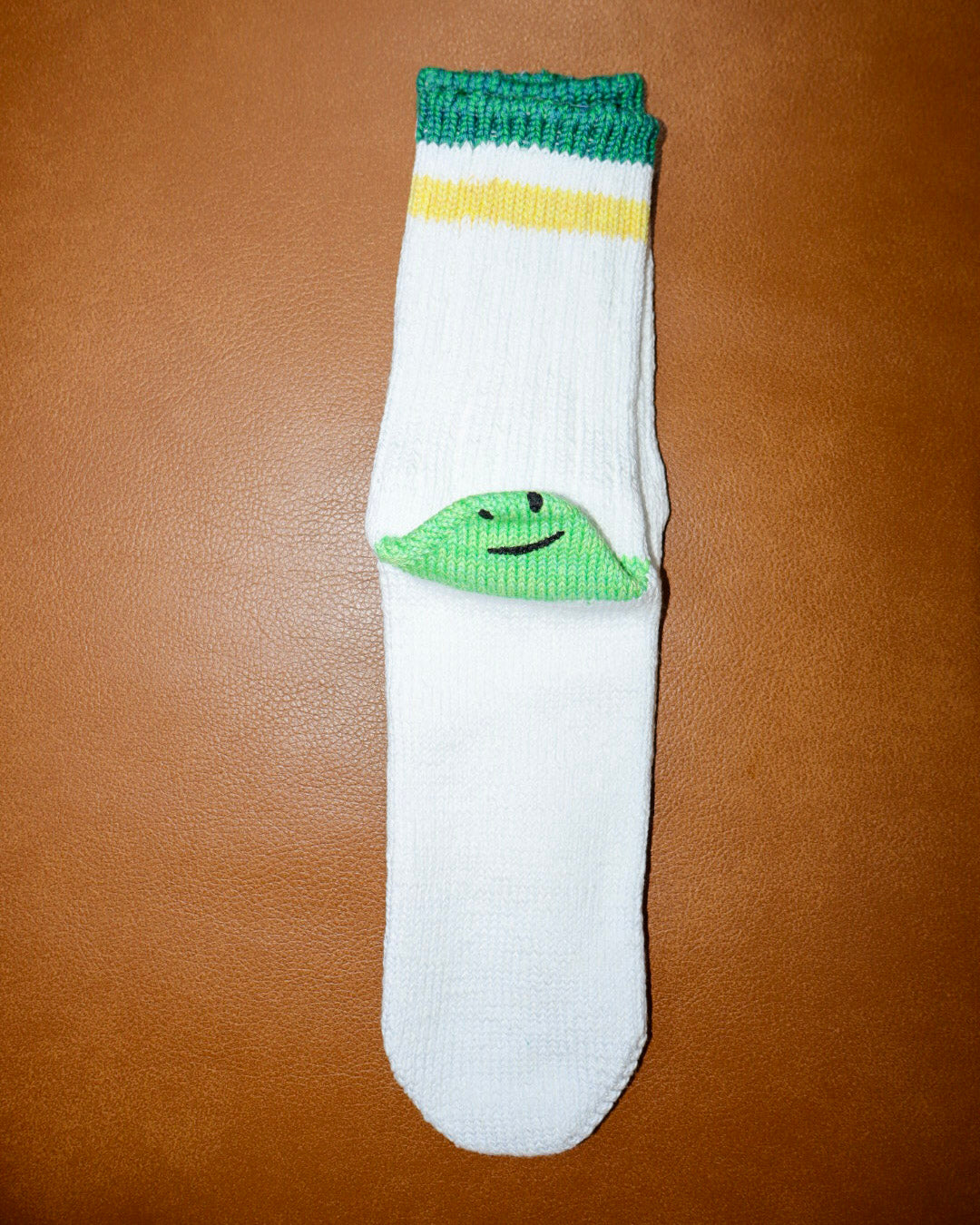 White sock with green frog design on a brown surface