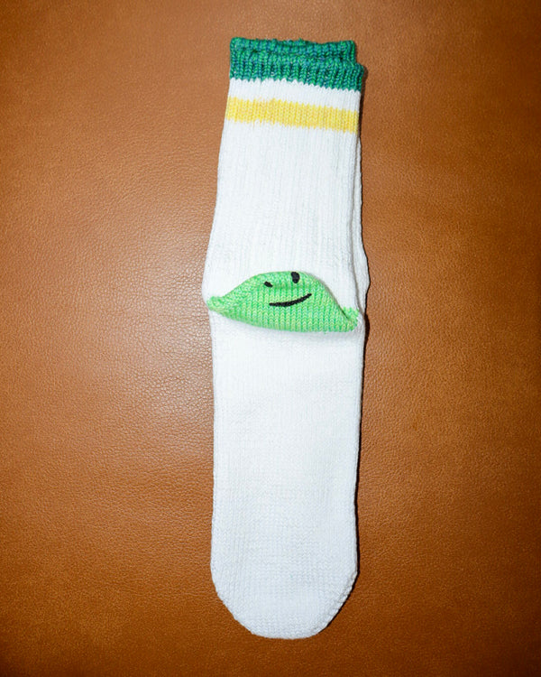 White sock with green frog design on a brown surface