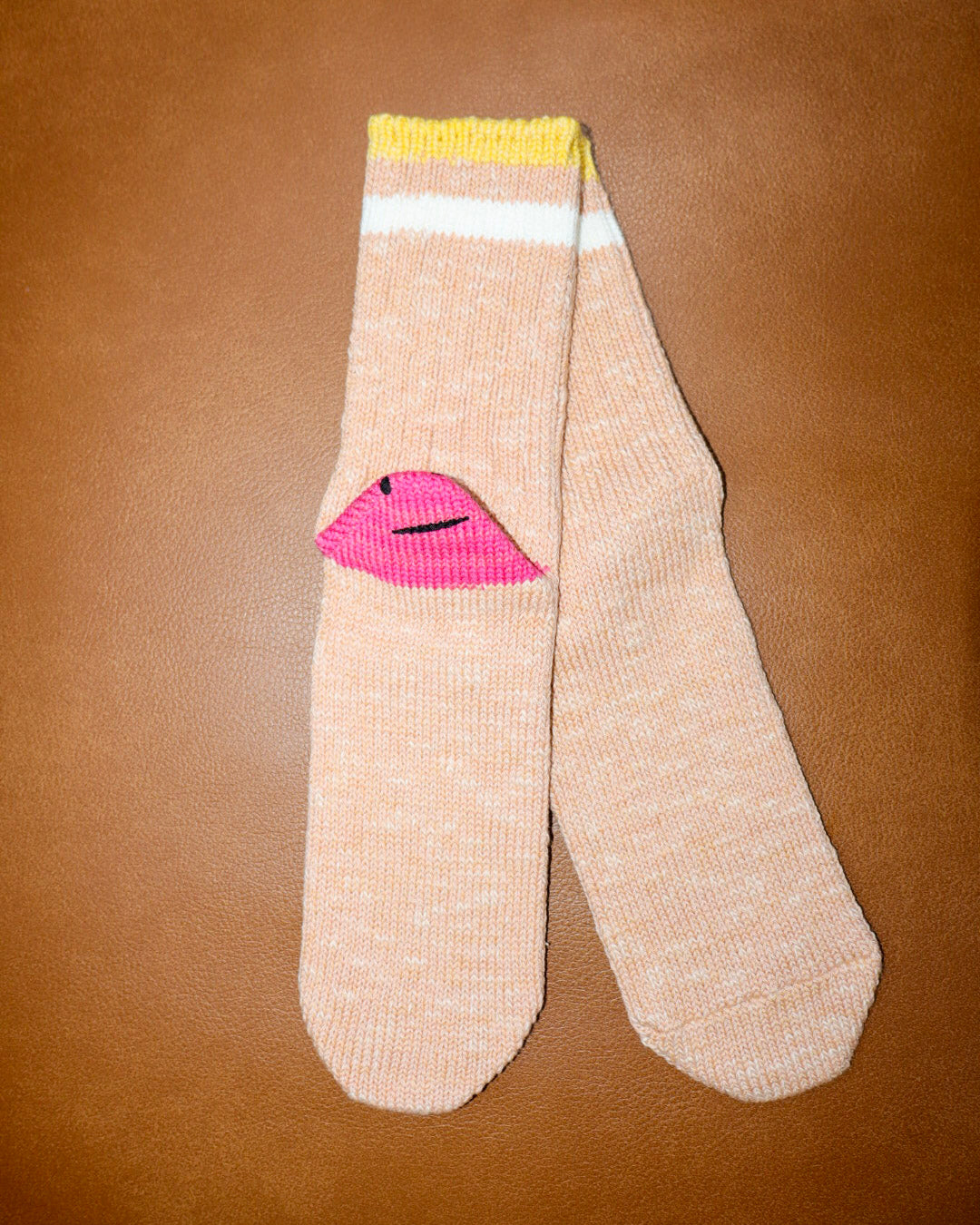 Beige sock with pink lips design on a brown background