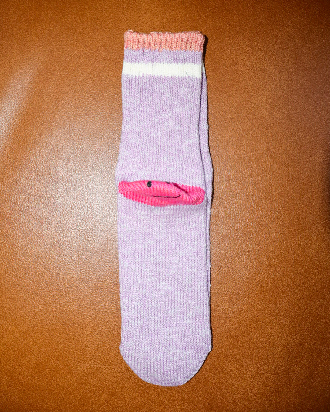purple sock with pink accents on a brown surface