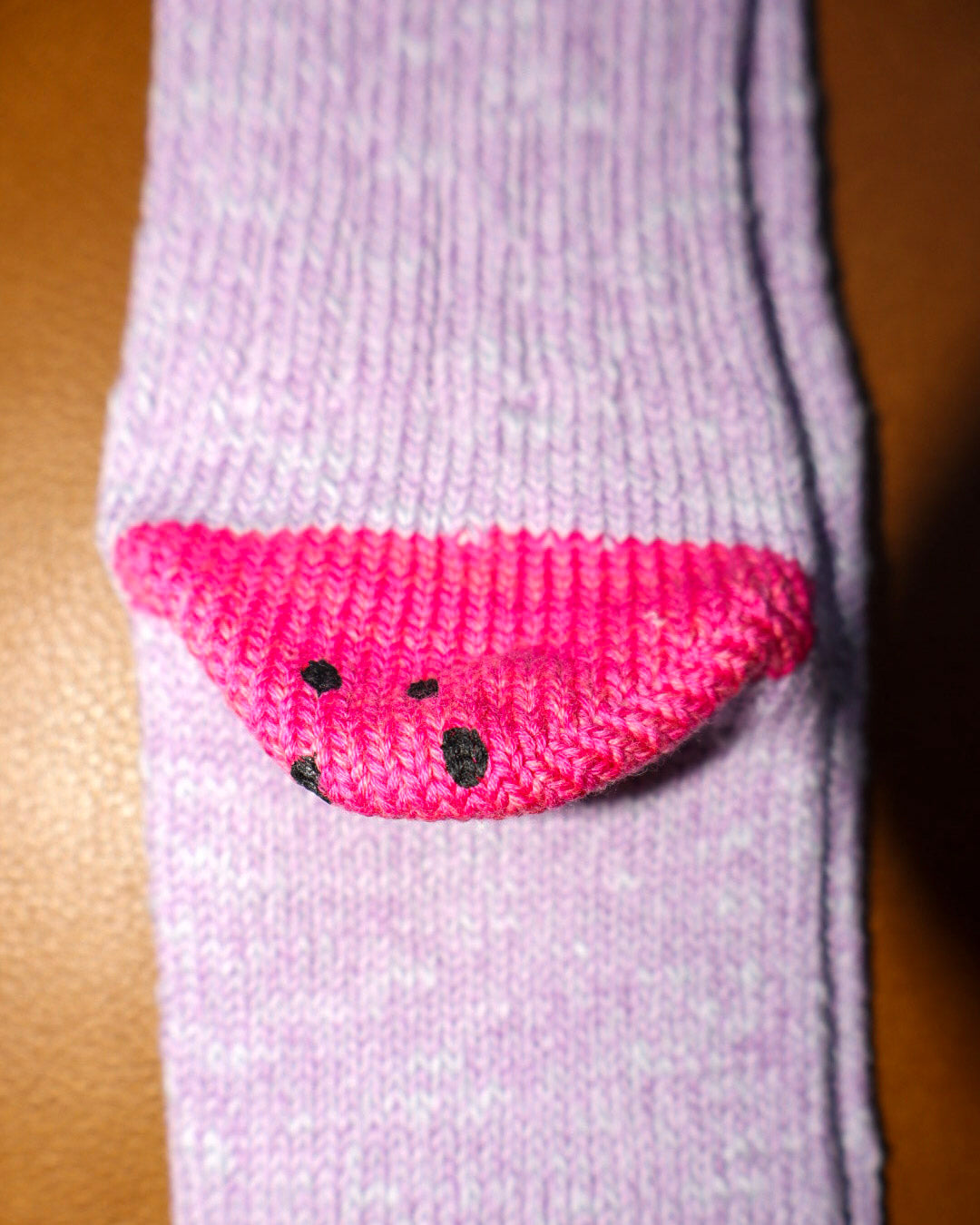 Purple sock with pink watermelon design on a brown background