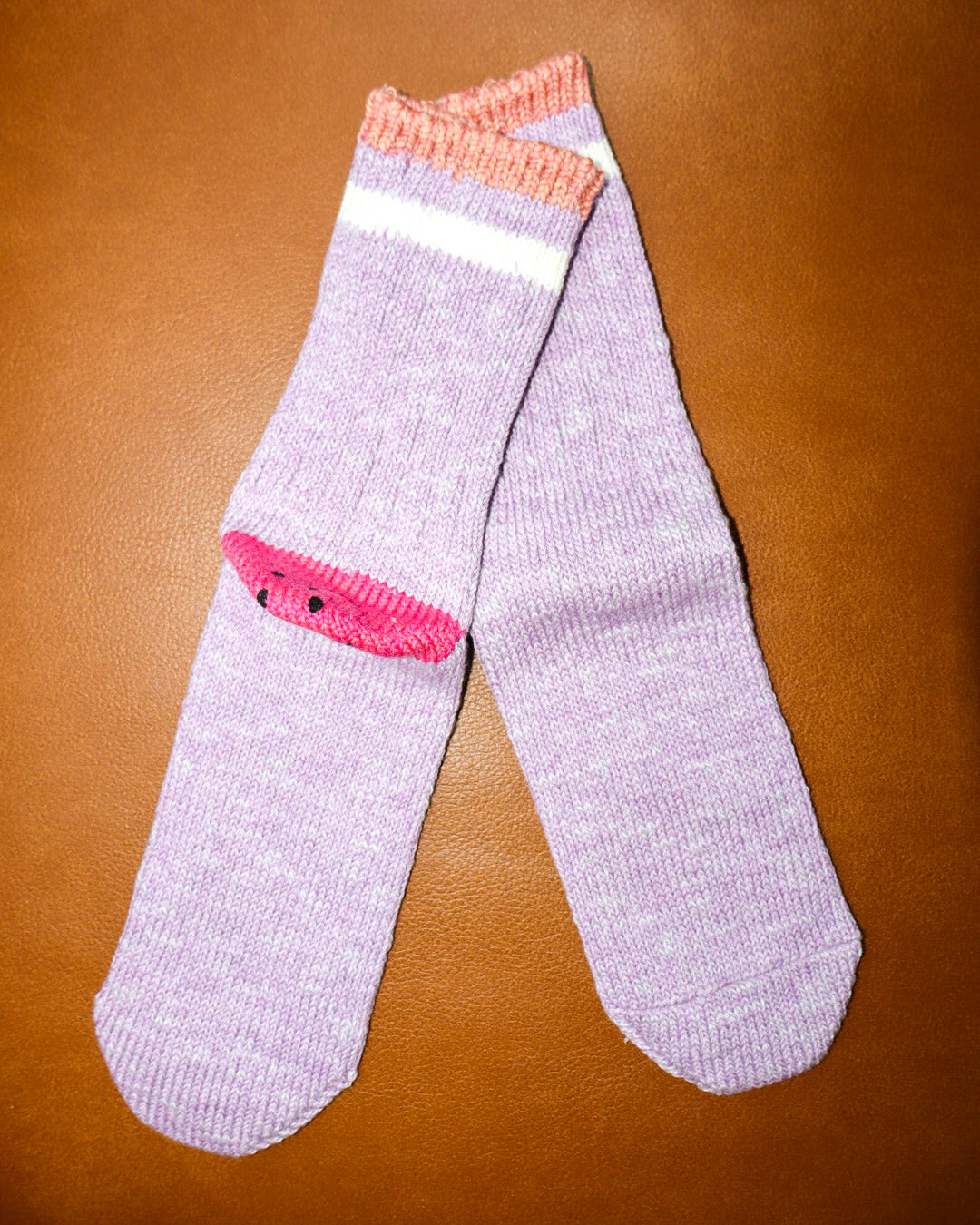 Pair of purple socks with pink accents on a brown surface