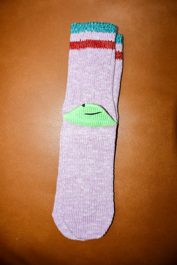 Gray sock with colorful top and green heel on a brown surface