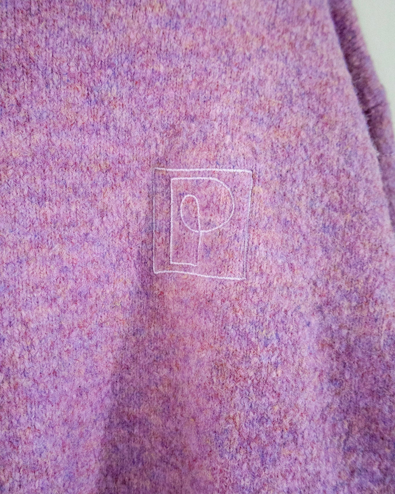 Close-up of a textured purple fabric with a logo on a plain background