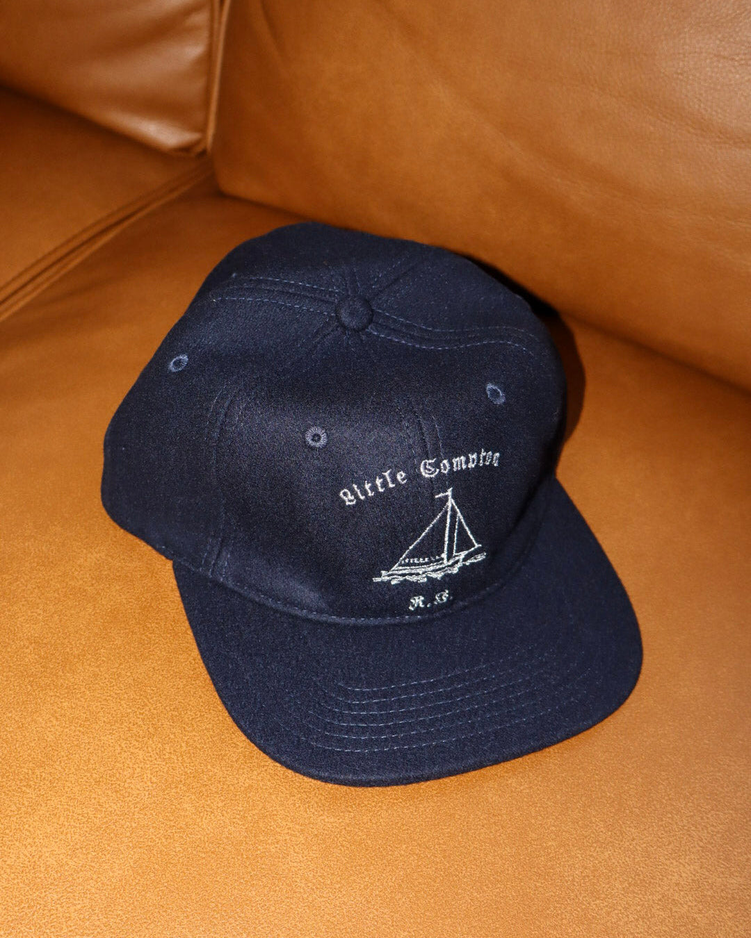 Navy blue cap with white logo on a brown leather surface