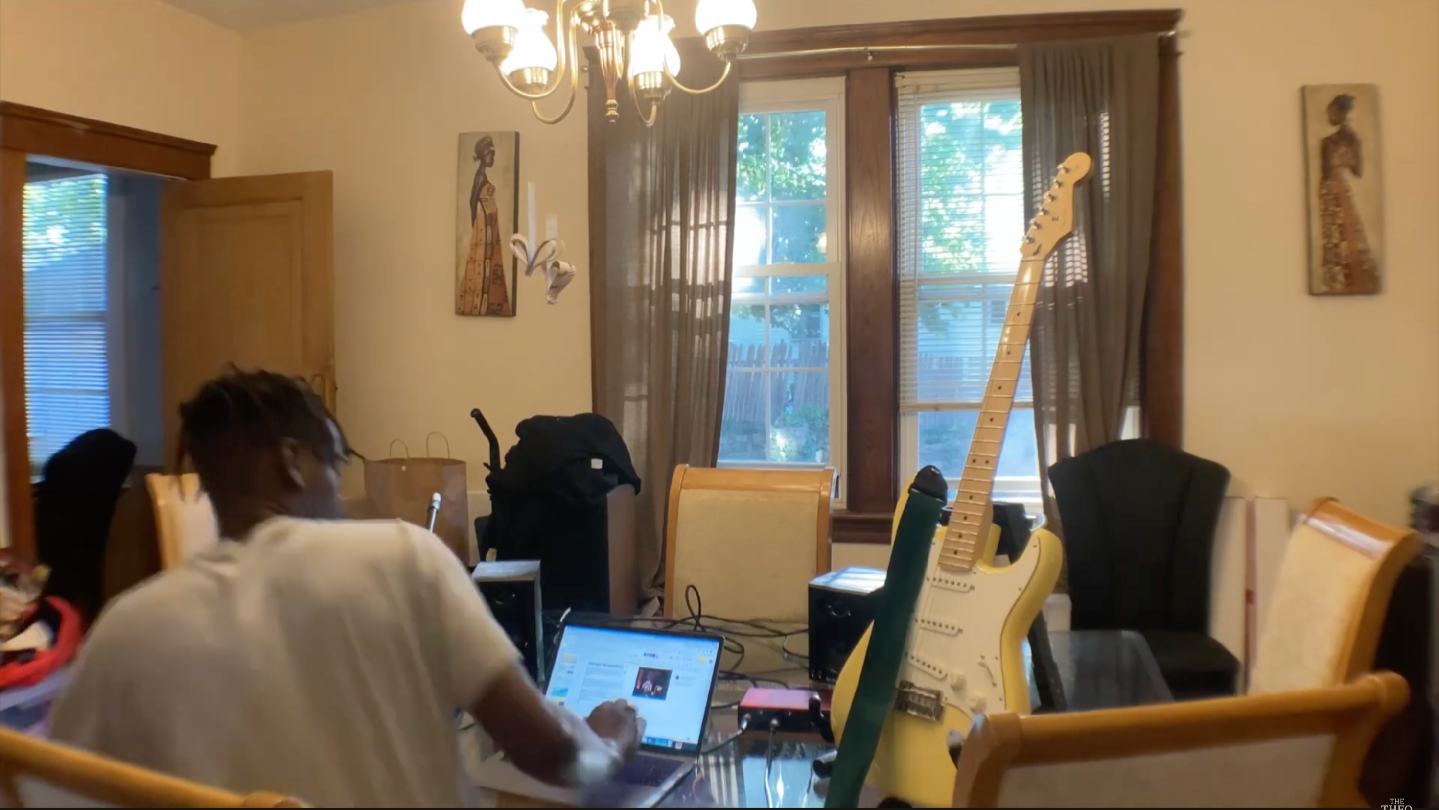 Person using a laptop in a room with musical instruments and decor.