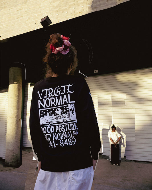 Person wearing a black sweatshirt with white text and graphics, standing in an urban setting.
