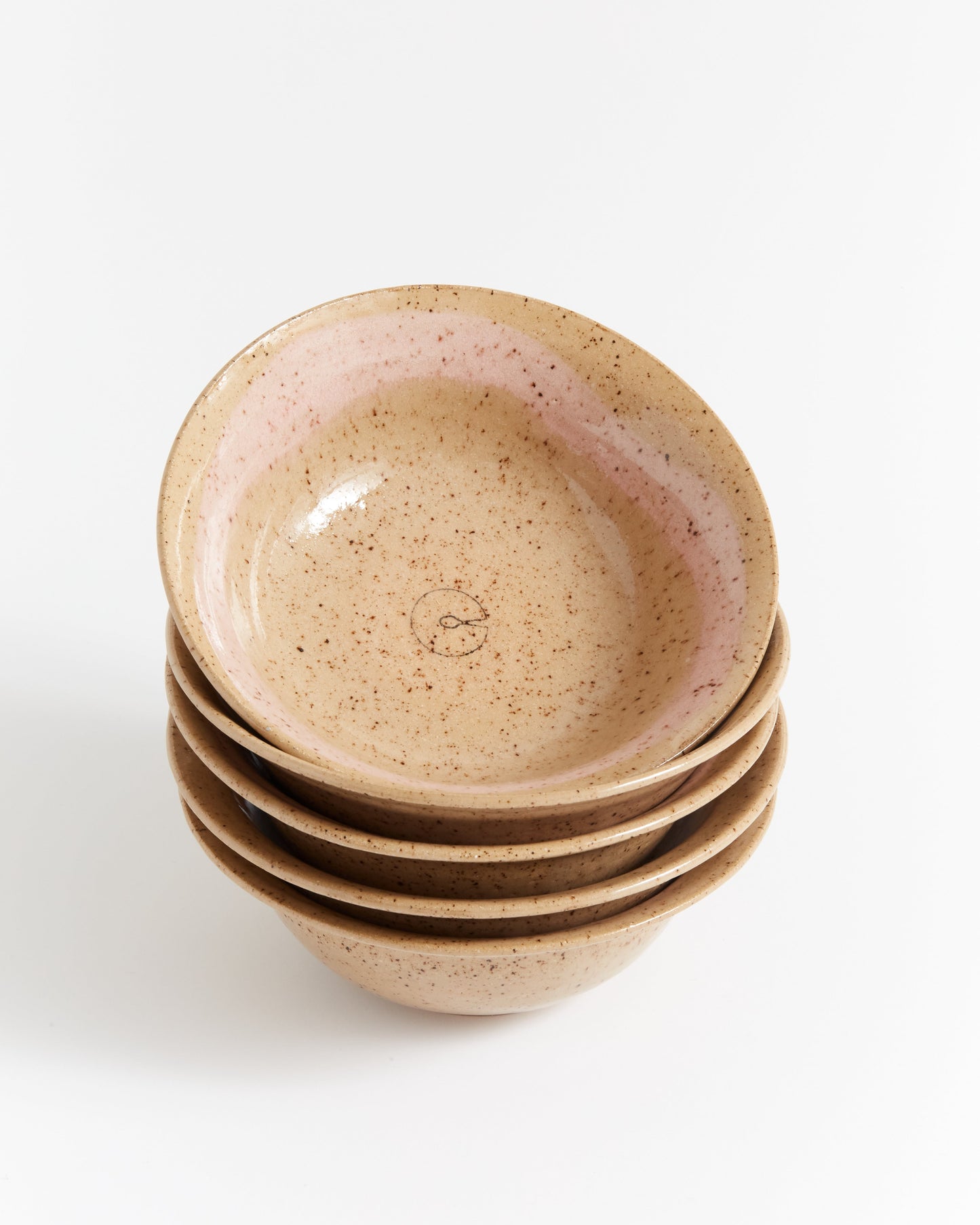 Stack of ceramic bowls with speckled glaze on a white background