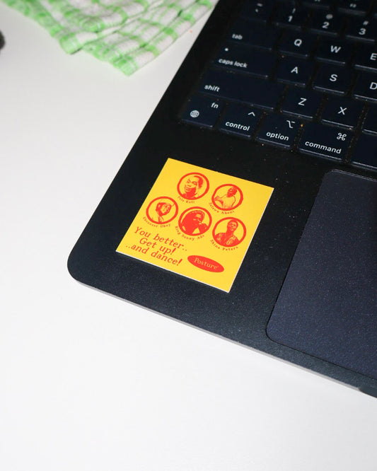 A square yellow sticker with red circular portraits and the text 'You better get up and dance!' applied to the palm rest of a black laptop.
