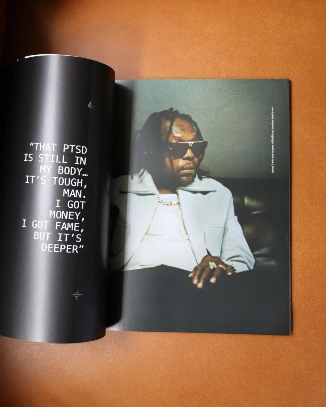 Book or magazine with a photo of a person wearing sunglasses and text on a brown surface