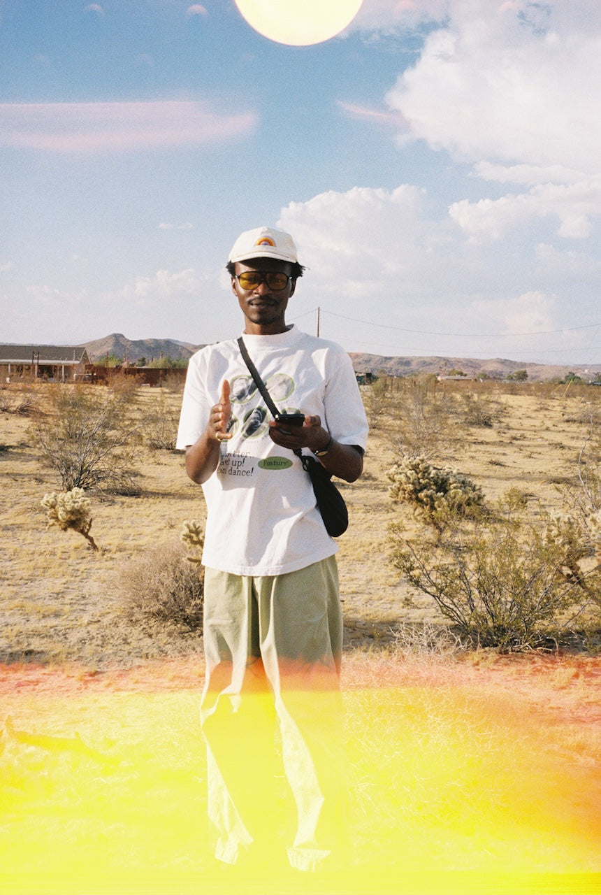 Person standing in a desert landscape with a yellow powder on the ground