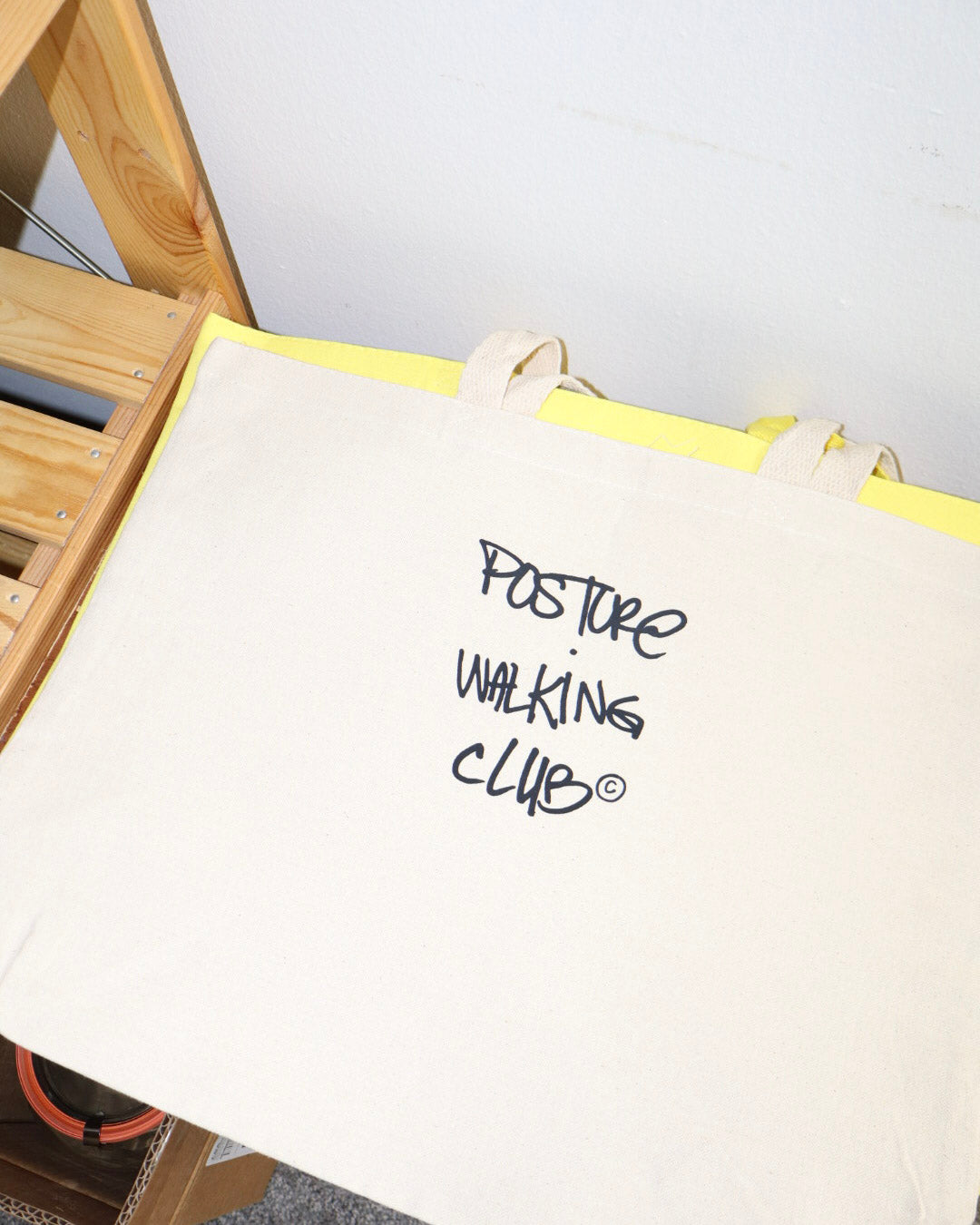 A cream canvas tote bag with text 'Posture Walking Club' printed